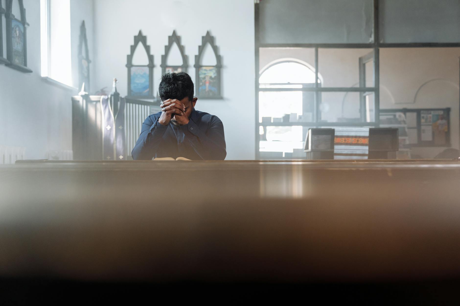 Mężczyzna pogrążony w modlitwie w nasłonecznionym, cichym pokoju