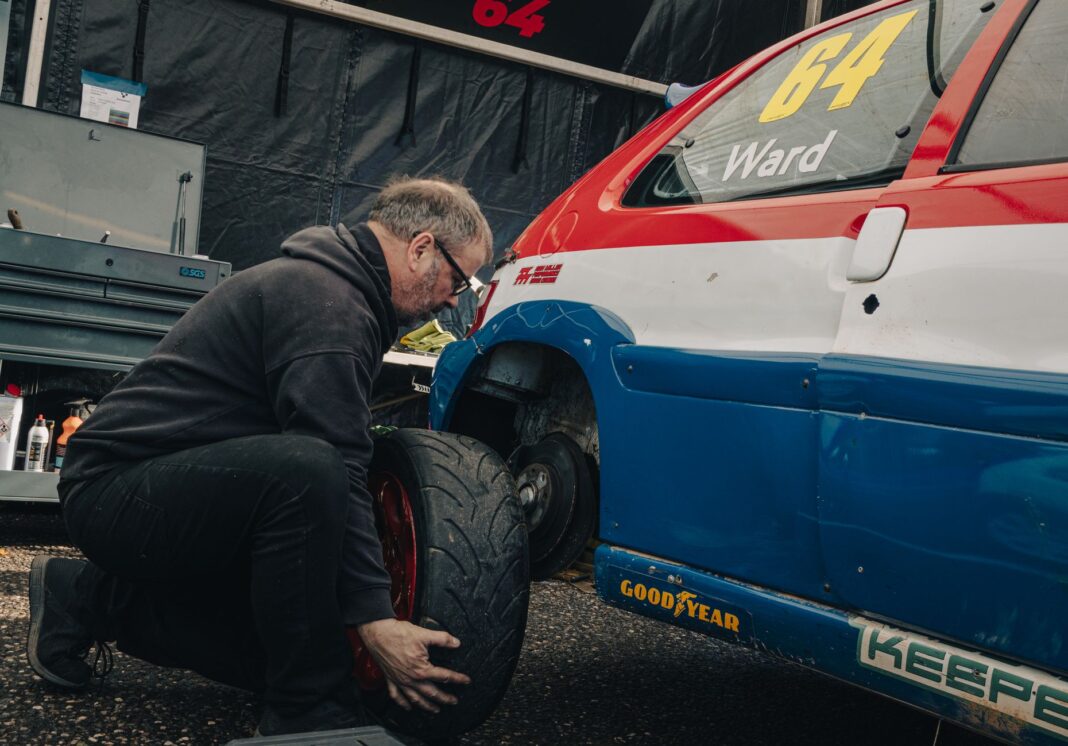 Mechanik wymienia oponę w niebiesko-czerwonym samochodzie wyścigowym Mechanik wymienia oponę w niebiesko-czerwonym samochodzie wyścigowym