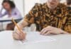 Przeniesienie profilu PKK do innej szkoły jazdy – formalności w urzędzie i OSK Młoda osoba pisząca ołówkiem test w sali egzaminacyjnej
